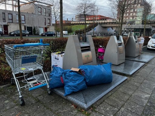 Afvalcontainers, een winkelwagentje en blauwe zakken op een trottoir.